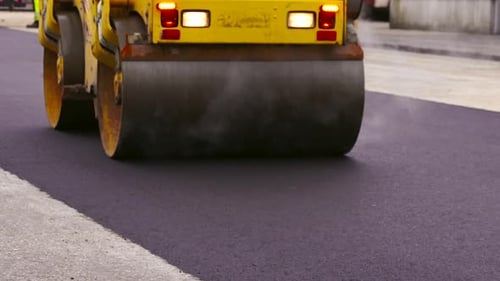 Asphalt Paving. Road Roller Drives Over Hot, Steaming, Freshly Layed Asphalt.