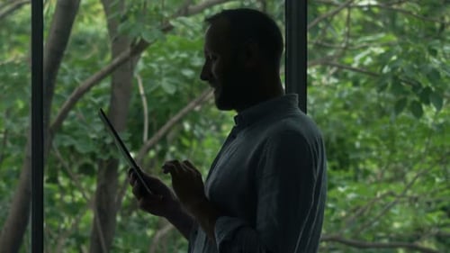 Man Using Tablet Device by Large Window