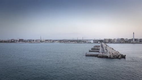 Cement blocks along pier at harbor with cityscape in background