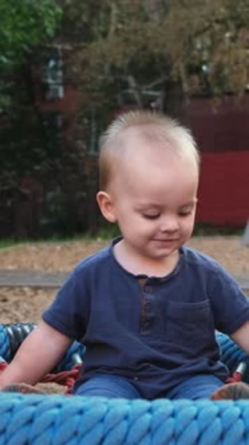 Joyful Infant Smiling on Rope Swing in Park