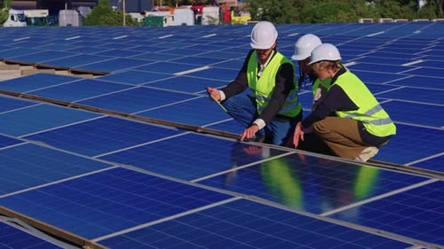 Gruppe von Ingenieuren, die Sonnenkollektoren auf einem Dach inspizieren