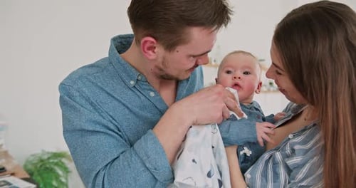 Happy Parents Cleaning Baby's Mouth in Kitchen After Mealtime