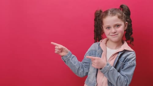 Portrait of shocked funny joyful little kid girl point fingers aside with copy space