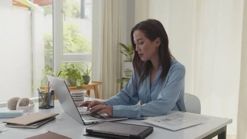 Businesswoman Sitting at Desk when Working on Laptop in Modern Office Space