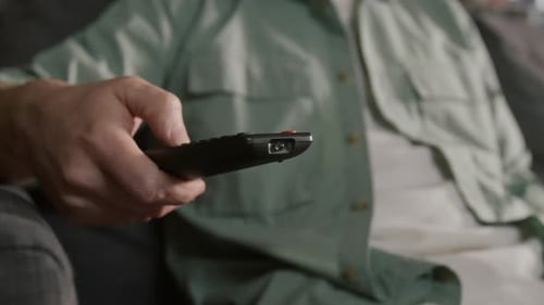 Unbekannter Fernsehzuschauer, der zu Hause eine Sendung mit Fernbedienung auswählt