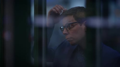 Man Wearing Glasses Looks Thoughtful Indoors
