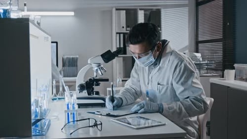 Scientist Examining Sample Through Microscope in Laboratory