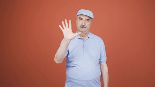 Old man making stop sign for camera.