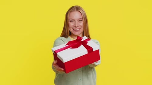 Smiling Woman Offering Gift Box on Yellow Background