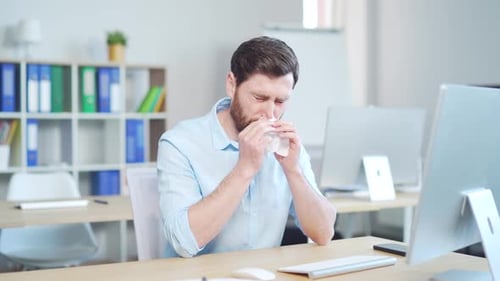 Man Sick at Work with a Cold