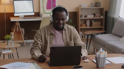 Young Adult Working at Computer with Headphones