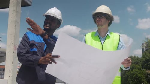 Construction Workers Reviewing Blueprint on Building Site