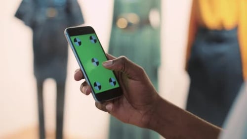 Nahaufnahme eines Mannes, der sein Telefon mit vertikalem grünem Bildschirm benutzt, im Einkaufszentrum, Finger mit den Händen nach Hause halten