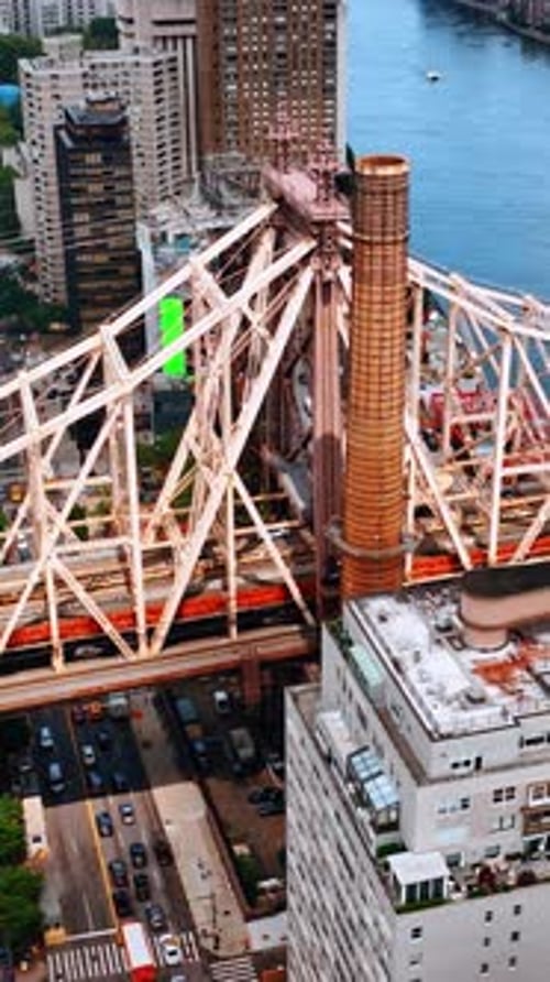 Support of the Queensboro Bridge above Hudson River. Multiple cars drive by the roads of New York