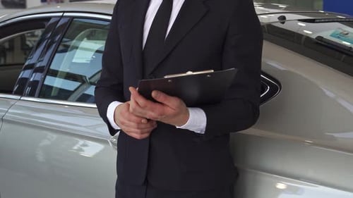 Car Salesman Stands Next to Car