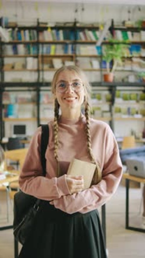 Uma estudante sorridente de óculos usando uma saia xadrez de líder de torcida segura uma mochila e livros em um
