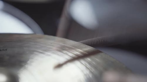 Drumsticks rapidly hitting hi-hat cymbal. Close up handheld.