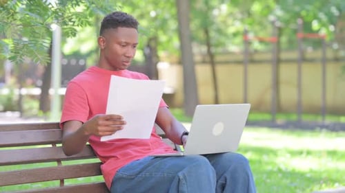 Man Working on Laptop in Urban Park Setting