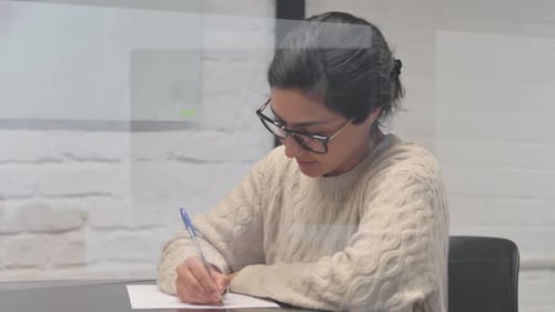 Woman Writing at Desk in Office