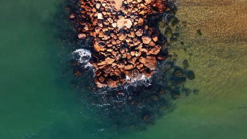 Vista aérea de cima para baixo do cais de pedra no mar. Extensão da estrutura rochosa do quebra-mar