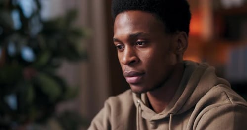 Young Man Focused Indoors in Hoodie