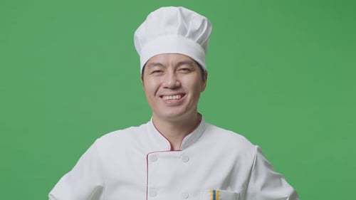 Close Up Of Asian Man Chef With Arms Akimbo Looking At Camera And Smiling In The Green Screen