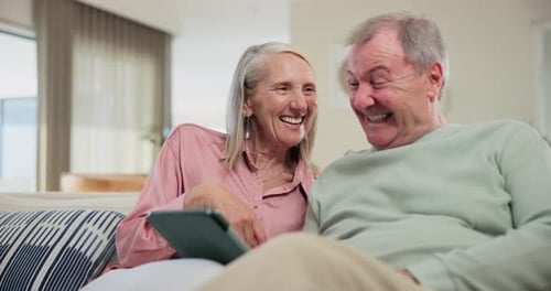 Senior Couple Laughing at Tablet on Sofa