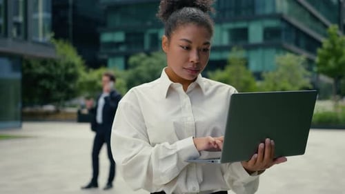Femme d'affaires afro-américaine, femme tapant un ordinateur portable à l'aide d'un ordinateur, travail en ligne dans une ville caucasienne