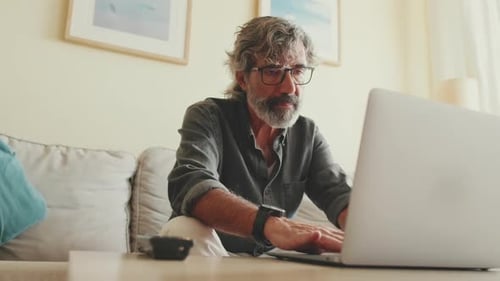 Adult Man Typing on Laptop in Home Setting
