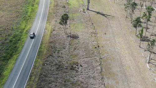 Drone flying along road in rural landscape, Bajool. Queensland in Australia. Aerial top-down forward