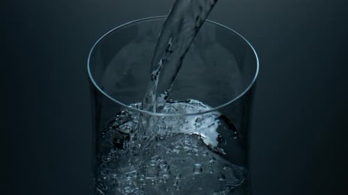 Refreshing pure water bubbling and filling a glass jug in slow motion