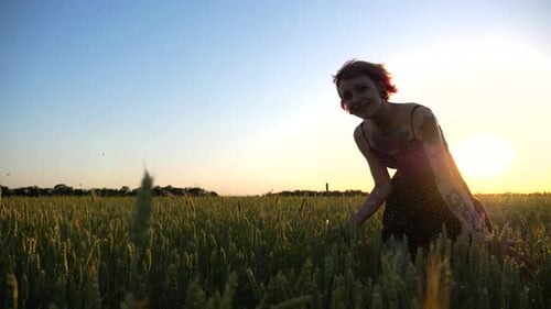 Happy Punk Woman with Tattoos Jogging Through Wheat Meadow at Beautiful Sunset Joyful Female Hipster