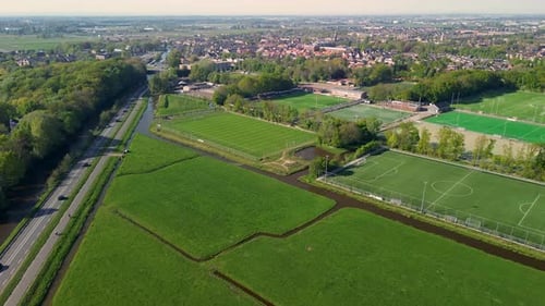 Vue aérienne d'en haut d'un terrain de sport verdoyant avec des marques blanches entouré d'arbres et de sentiers