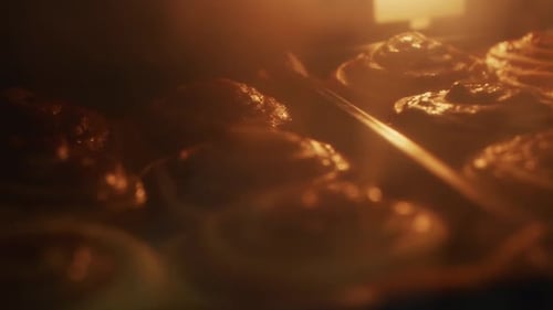 Bakers dozen of cinnamon rolls baking in over, filmed as handheld close up shot