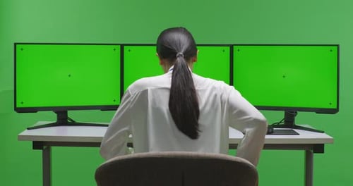 Woman Sit Down And Working With Mock Up Multiple Computer Monitor In Green Screen Studio