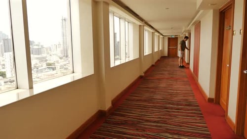 Man Walking Confidently in Hotel Corridor with City Skyline Views