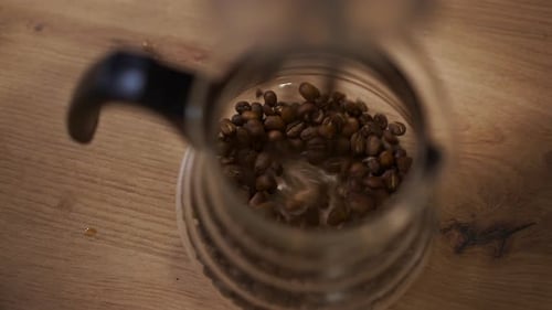 High Angle View Transparent Glass Jar with Coffee Beans Falling Inside in Slow Motion Closeup