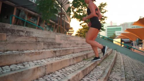 Woman Running Up Steps in the City at Sunrise