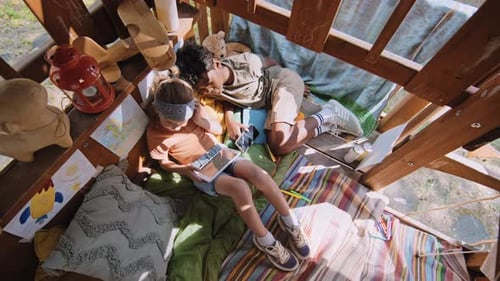 Two Children Relaxing Inside a Treehouse
