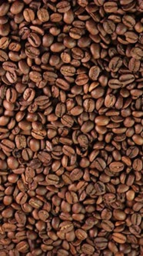 Vertical video roasted coffee beans rotating as background close-up wide angle. Concept for coffee
