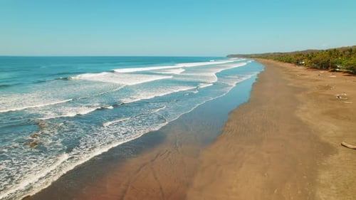 Long sandy beach with waves rolling gently along the Pacific coast of Costa Rica