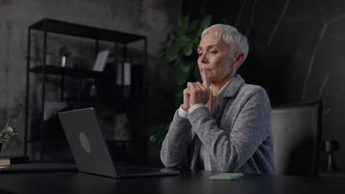 Mature Woman Typing at Laptop in Dim Office