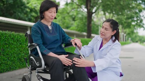 Nurse discussing an elderly lady's knee pain. Happy nurse, wheelchair and elderly care in garden
