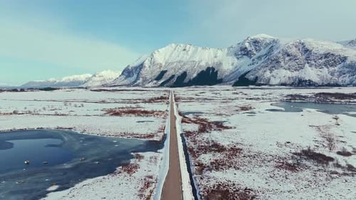 Stunningly Scenic Winter Roadway Meandering Through Snowy Mountains and Open Fields