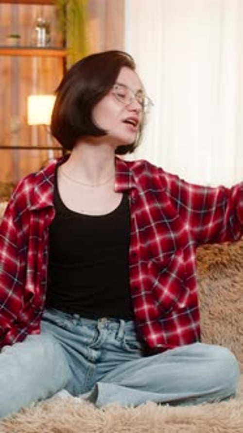 Jeune femme répétant un monologue à la maison, faisant des gestes avec émotion et engagement théâtral total