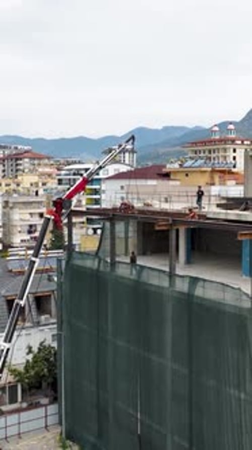Vídeo vertical a vista de pájaro de trabajadores de la construcción descargando vigas metálicas en un
