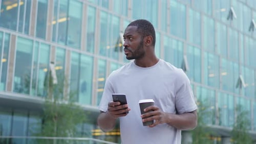 Good Morning African Man Drinking Coffee to Go Holding Smartphone Walking on Street in City Man with