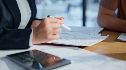 Hands Analyze Blueprints with Calculator in Office