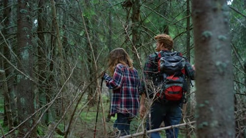 Positive Woman And Man Hiking Together In Green Forest. Smiling Tourists Having Adventure In Wood...