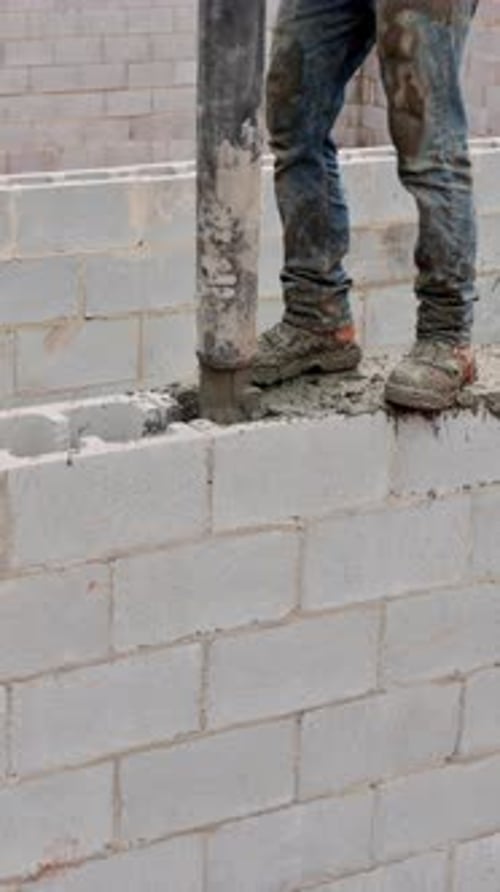 Construction Worker Laying Concrete in Blocks at Building Site